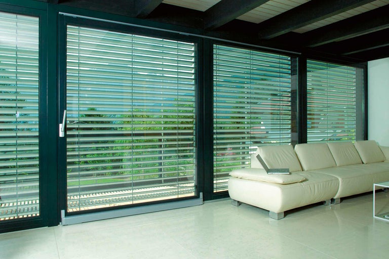 Innenaufnahme eines Wohnzimmers mit Fensterfront und Jalousien