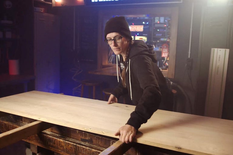 Femme manipule une plaque de bois dans un atelier