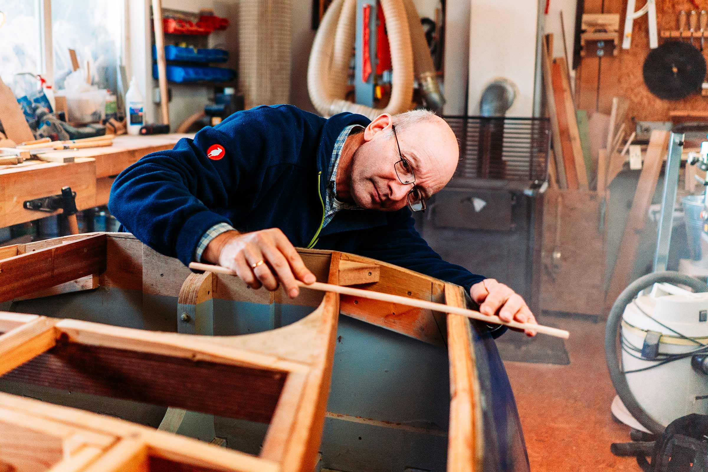 Un homme travaille sur un bateau en bois dans un atelier.