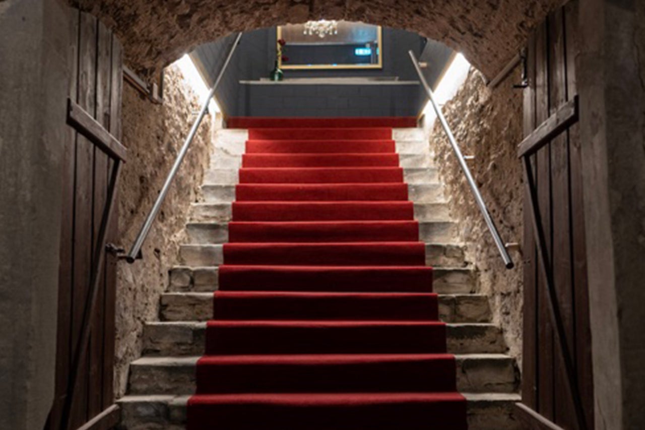 Steintreppe mit rotem Teppich und Metallgeländer in einem Gebäude