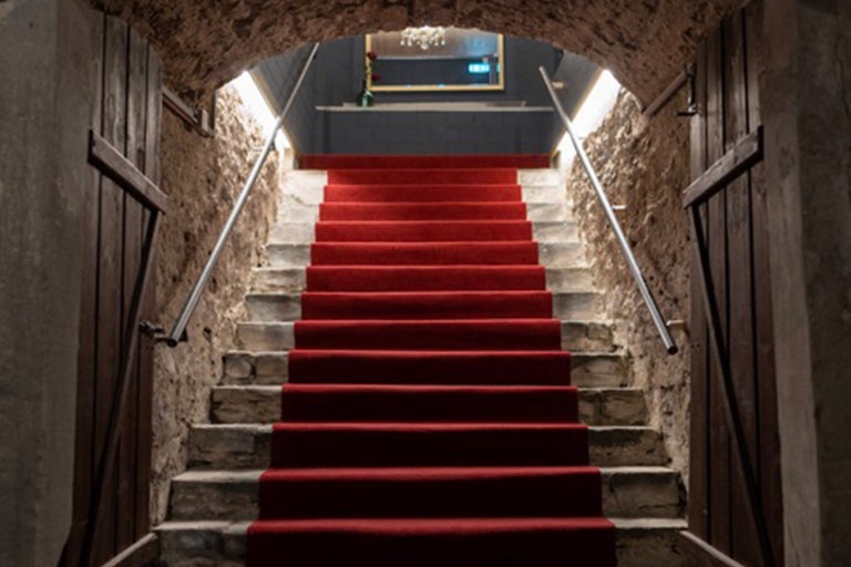 Escalier en pierre avec moquette rouge et rampe en métal dans un bâtiment