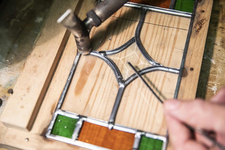 Löten einer Glasarbeit mit Lötkolben auf Holzrahmen