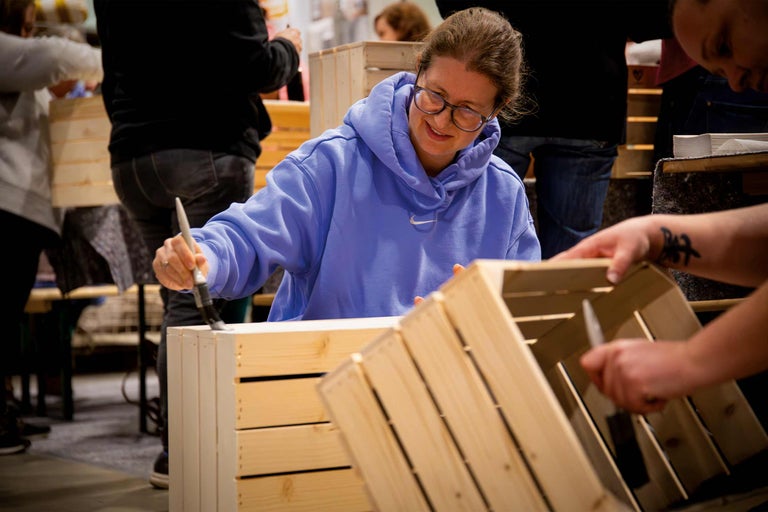 Une personne peint une caisse en bois avec un pinceau