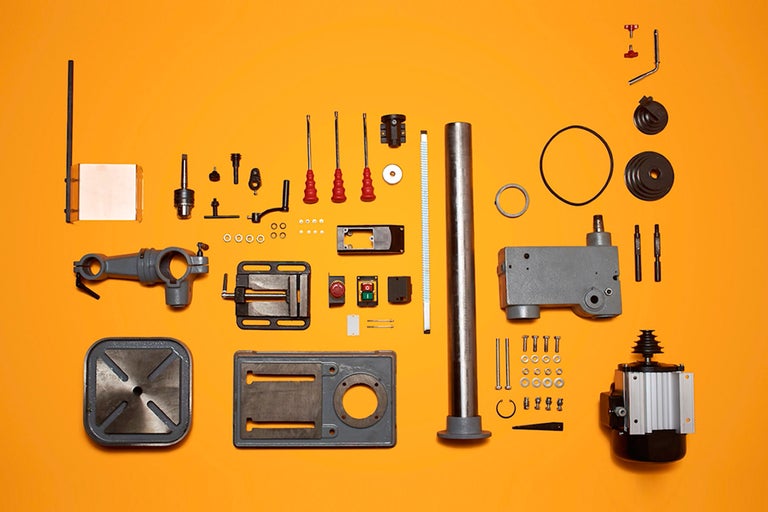 Einzelteile einer Standbohrmaschine auf gelbem Hintergrund