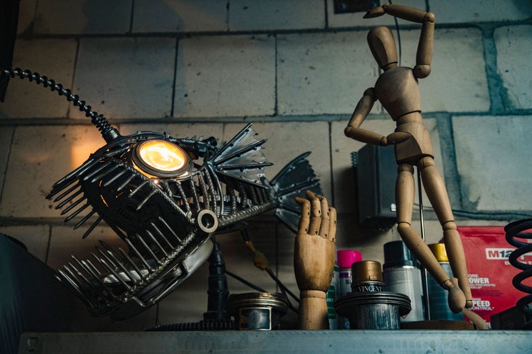 Scène décorative avec une lampe poisson en métal, un mannequin articulé en bois et un mannequin de main en bois