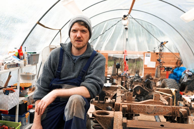 Mann in Werkstatt mit Werkzeug und Fahrzeugteilen