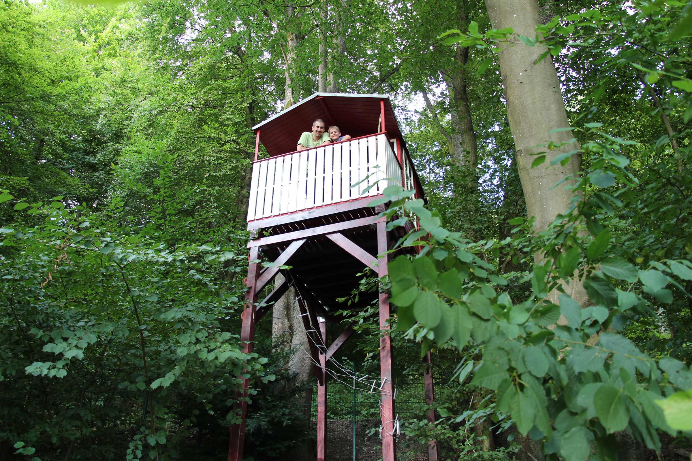 Ein Baumhaus aus Holz mit Personen im Wald