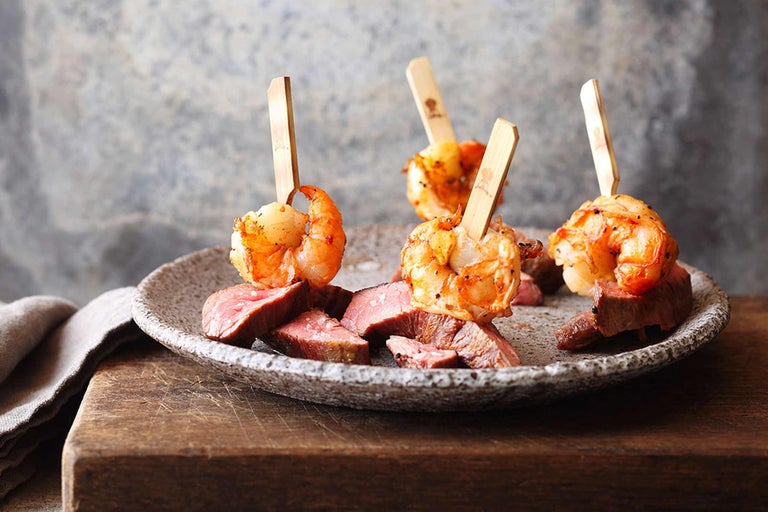 Teller mit gegrillten Garnelen am Spiess und Rindfleischstücken.