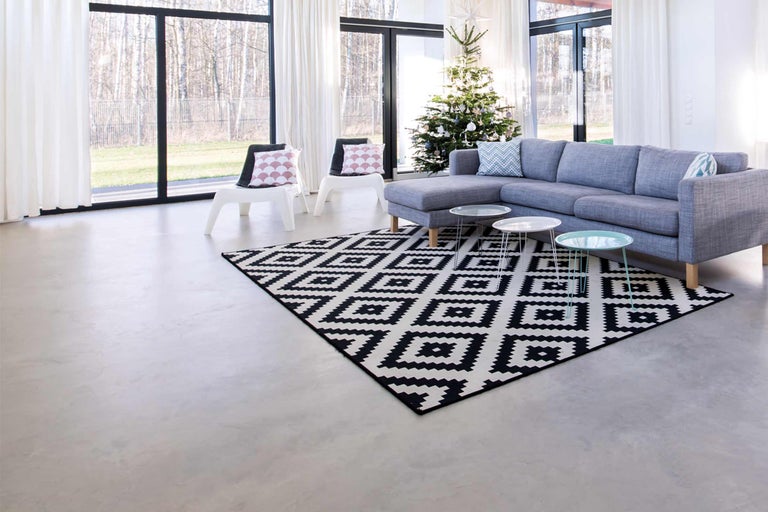 Salon avec canapé gris, tapis à motifs et sapin de Noël