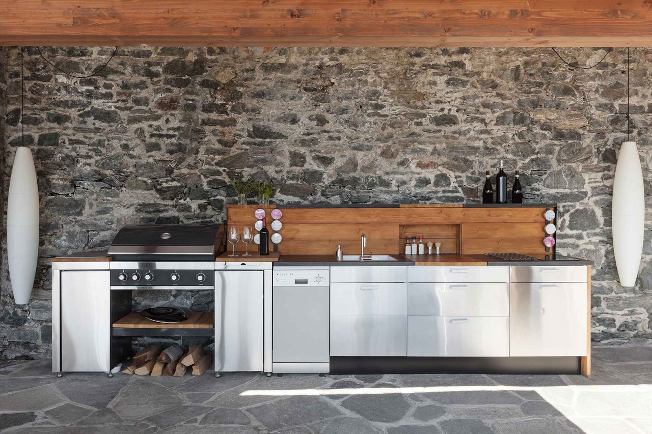 Cuisine extérieure avec barbecue, évier, plans de travail et mur en pierre