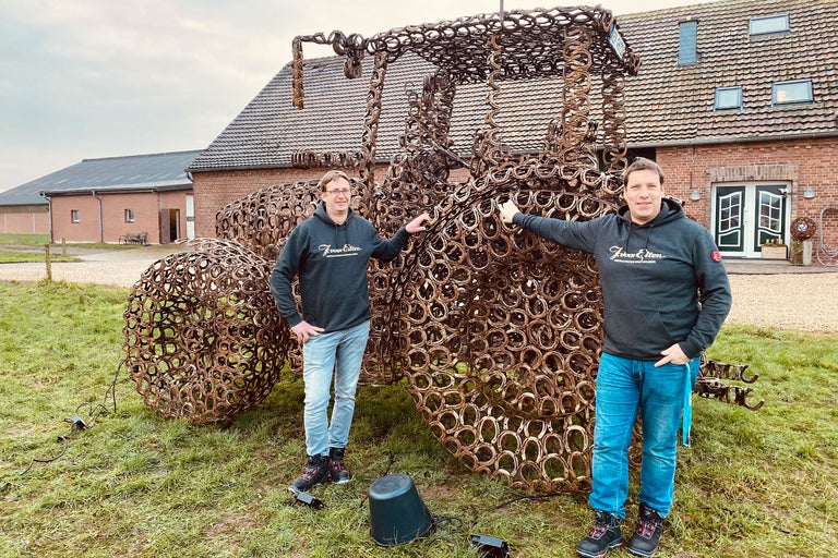 Sculpture d'un tracteur faite de fers à cheval avec deux personnes