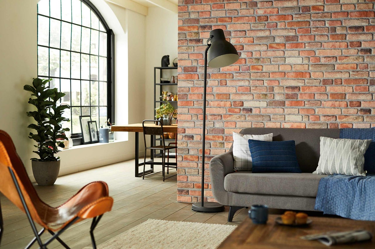 Salon avec mur en briques, lampadaire et fauteuil en cuir