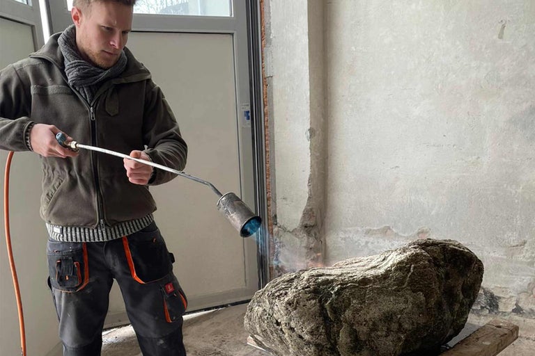 Un homme chauffe une pierre avec un brûleur à l'intérieur.