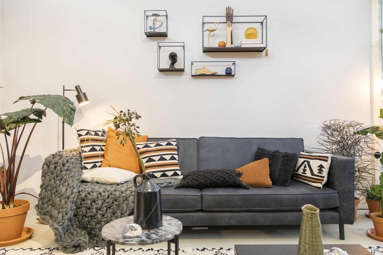 Salon avec canapé, coussins et étagères murales comme décoration de pièce