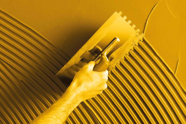 Artisan appliquant de la colle avec une spatule crantée