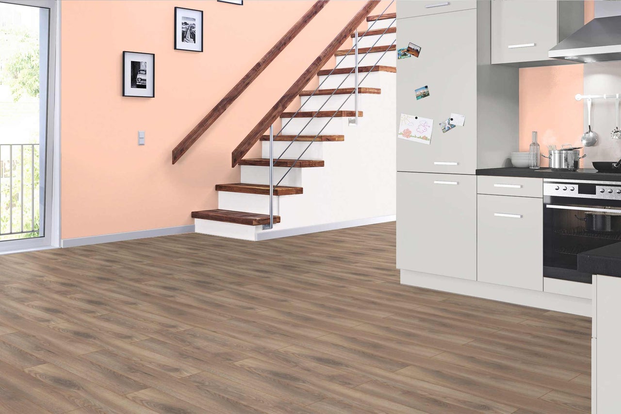 Pièce à vivre avec sol stratifié, escalier et kitchenette.