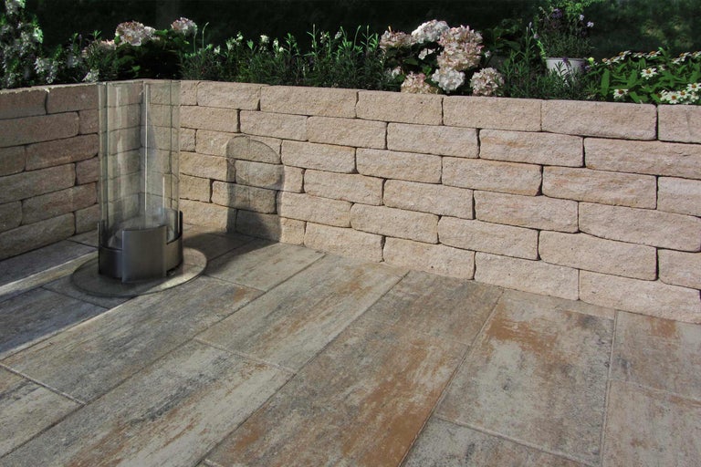 Scène de jardin avec un mur en pierre et des dalles de terrasse