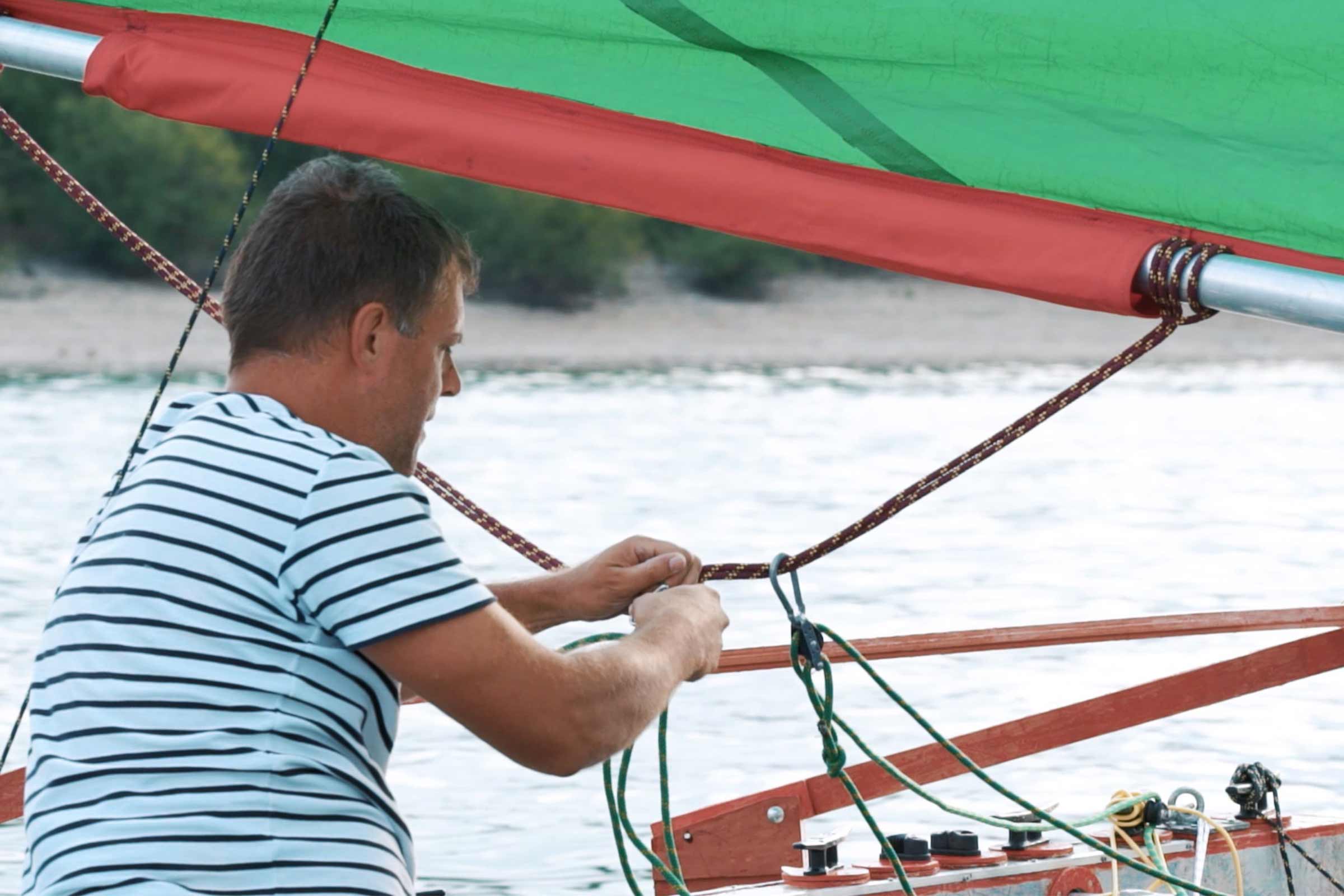 Un homme fixe une corde sur un voilier