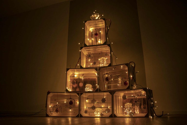 Dekorativer Weihnachtsbaum aus Holzkisten mit Lichterketten und Ornamenten