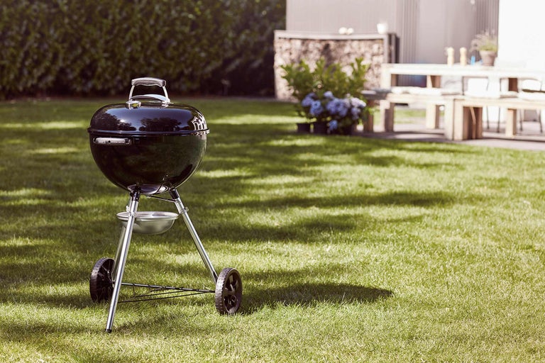 Barbecue sphérique sur une pelouse dans le jardin.