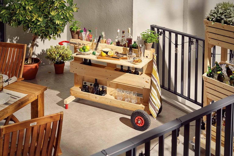 Photo d'un bar en bois sur un balcon, rempli de boissons et de verres.