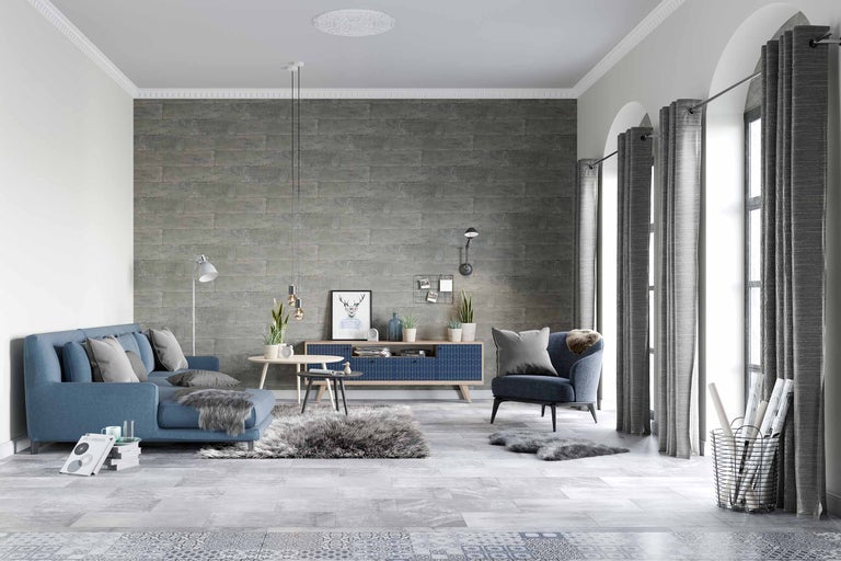 Wohnzimmer mit blauem Sofa, Sessel, grauen Vorhängen und gemusterter Wand