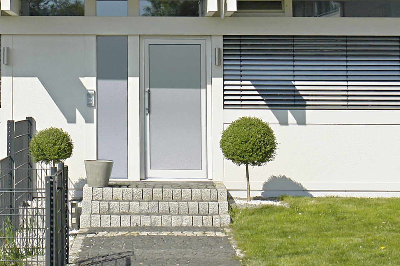 Maison moderne avec porte d'entrée, escalier en pierre et jardin