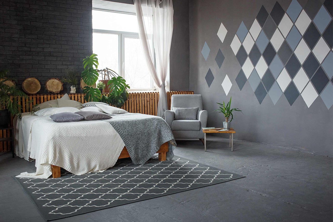 Chambre claire avec lit double, fauteuil, petite table et tapis