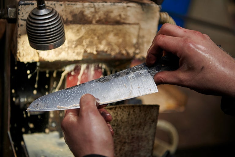 Une personne aiguise un couteau sur une meule.