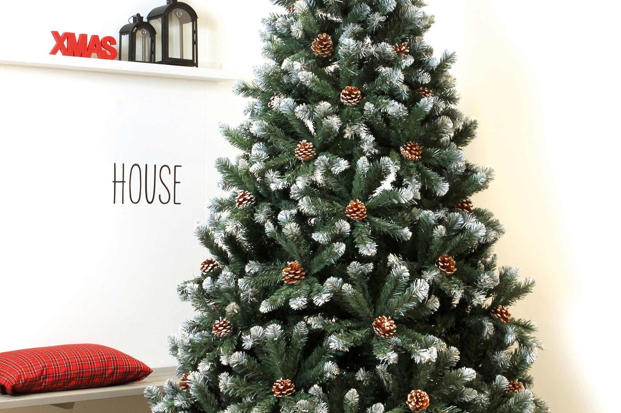 Sapin de Noël décoré avec des pommes de pin dans une pièce lumineuse.