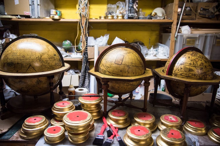 Trois globes sur socles en bois et socles peints avec des détails rouges sur un établi.