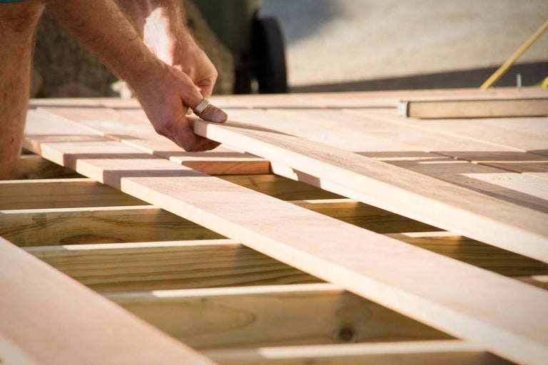 Un homme pose des planches de terrasse en bois sur une sous-construction