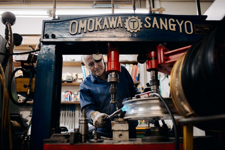 Un homme travaille avec un poste à souder sur un objet métallique dans un atelier.