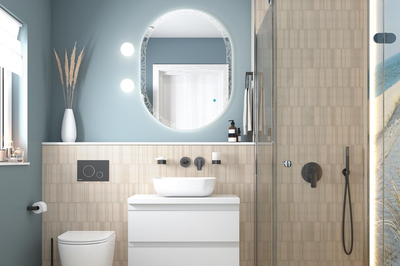 Salle de bains lumineuse et organisée avec meuble sous-vasque blanc, vasque à poser, mitigeur mural noir, miroir ovale lumineux et douche en verre.