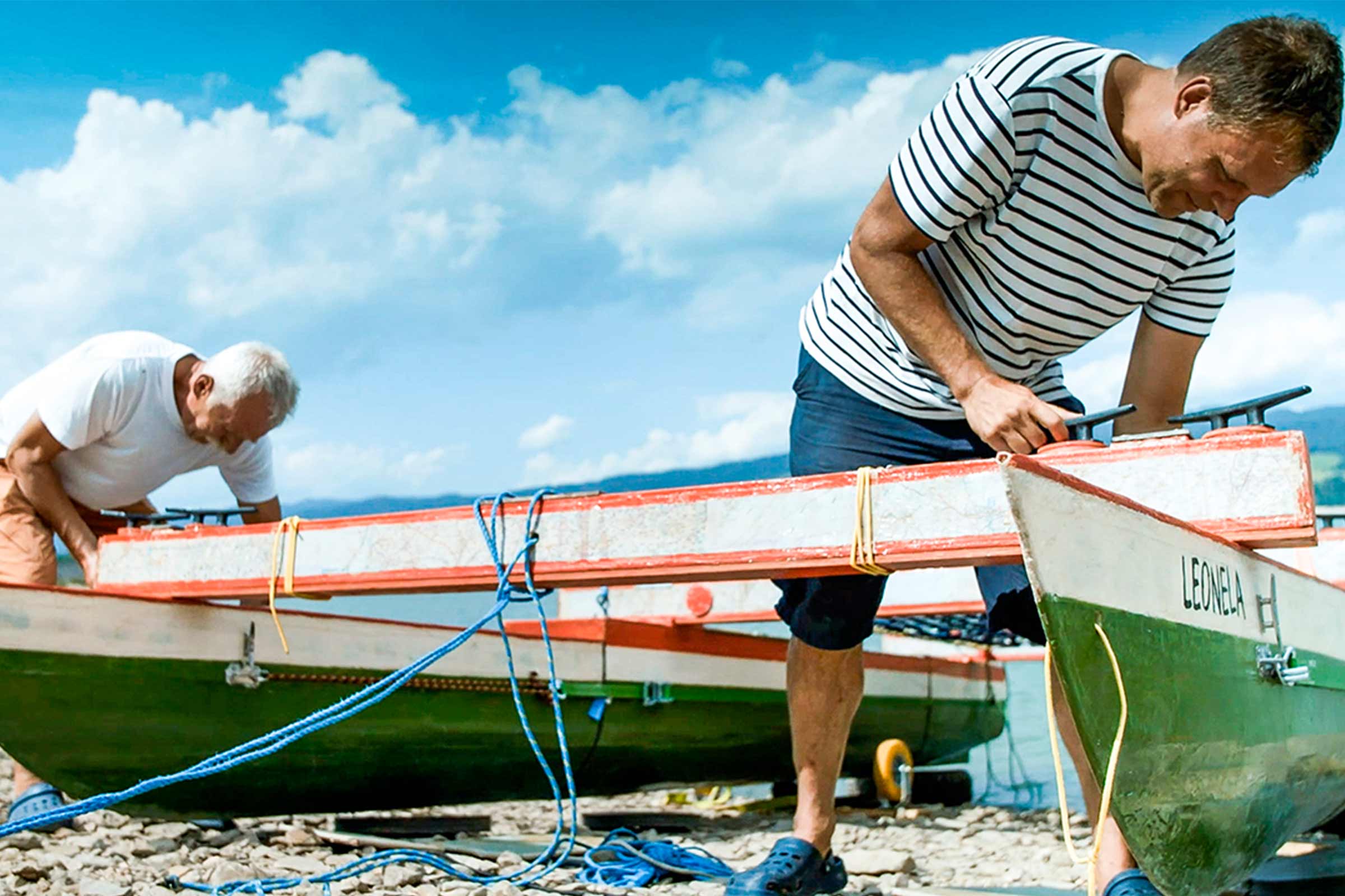 Deux hommes préparent des bateaux au bord de l'eau pour une promenade.