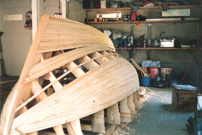 Holzboot im Bau mit Spanten und Planken in einer Werkstatt.