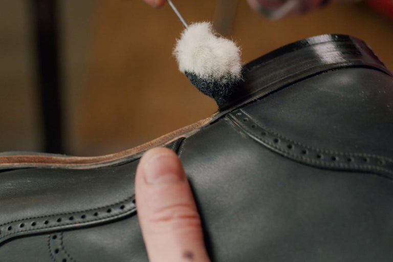 Gros plan d'une chaussure en cuir en cours de nettoyage avec un applicateur