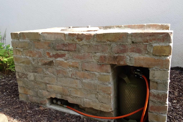 Gemauerter Grill mit Gasflasche und Gasschlauch