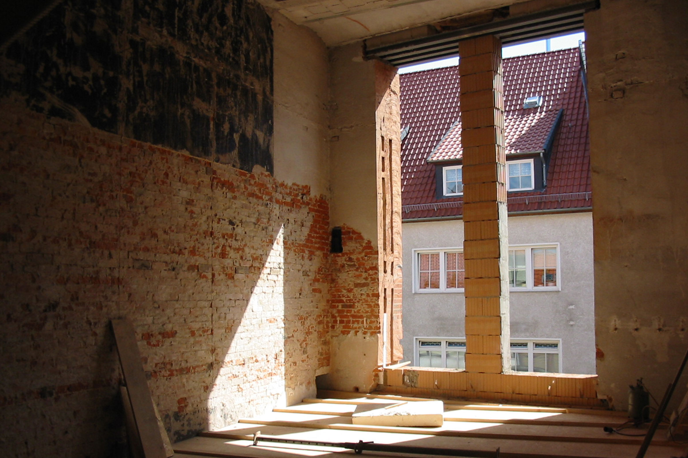 Intérieur d'un bâtiment en construction avec mur en briques et ouverture de fenêtre