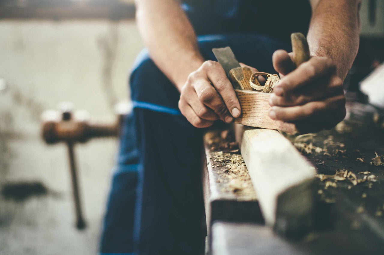 Artisan rabotant du bois avec un rabot