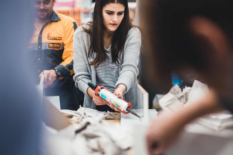 Une femme utilise un pistolet à cartouche pour les produits d'étanchéité.