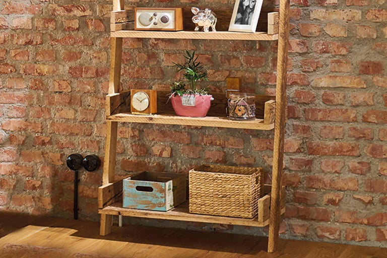 Étagère en bois avec éléments décoratifs devant un mur en briques