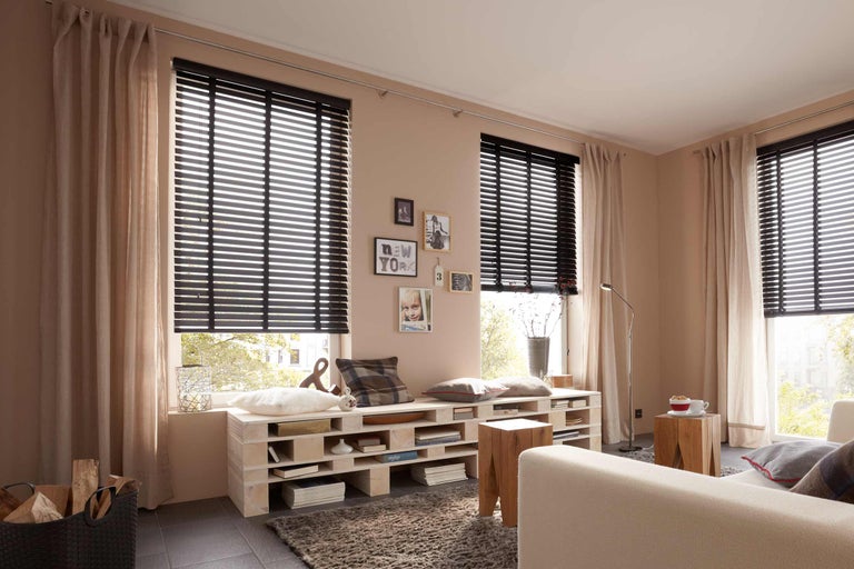 Wohnzimmer mit Holzjalousien, Vorhängen und Palettenmöbeln