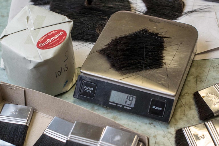 Poils de brosse sur une balance, à côté d'un emballage et de pinceaux