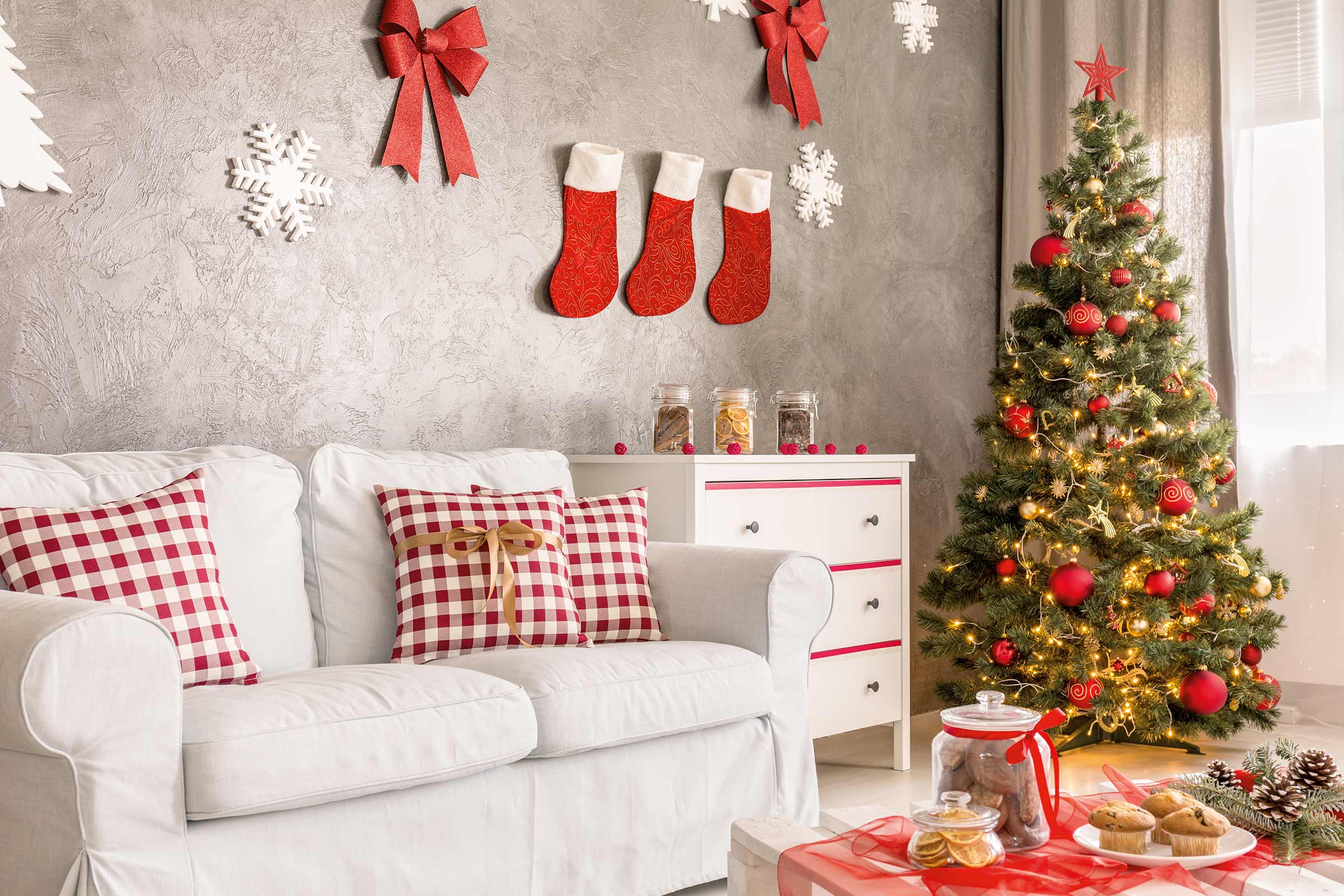 Weihnachtlich dekorierter Wohnraum mit Sofa, Weihnachtsbaum und Dekorationen