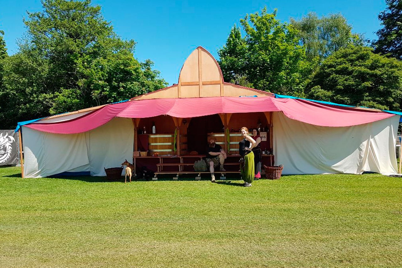 Scène avec un pavillon en bois recouvert de tissu sur une pelouse.