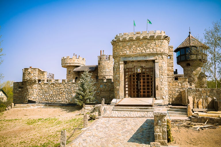 Aussenansicht eines Schlosses mit Steinmauern und Türmen unter blauem Himmel