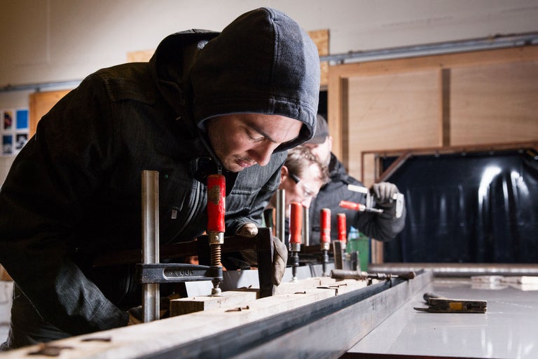 Deux artisans travaillent avec des serre-joints sur un cadre en bois sur un établi.