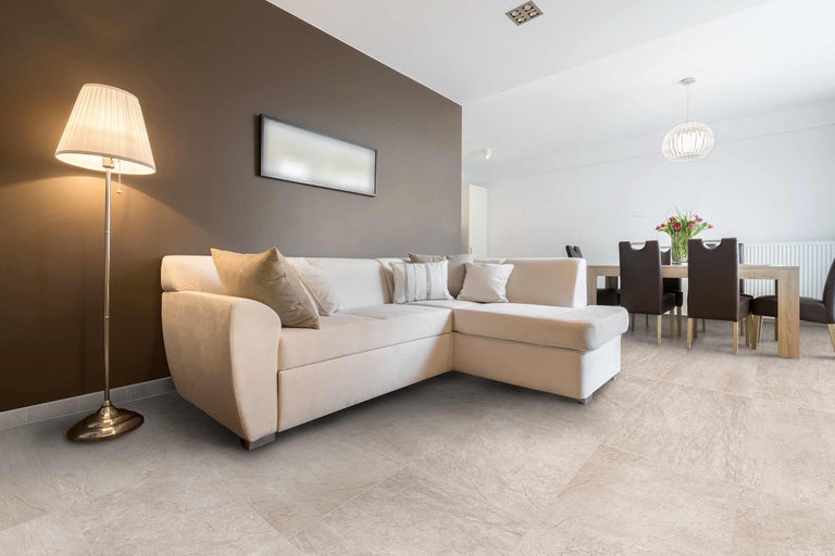 Wohnzimmer mit Ecksofa, Stehlampe und Fliesenboden