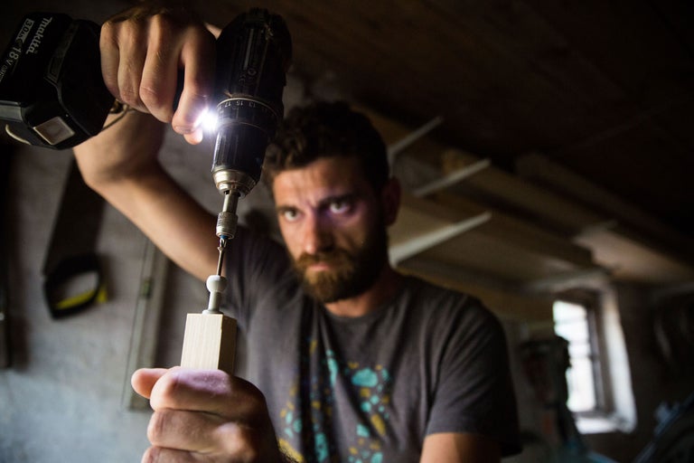 Ein Mann bohrt mit einem Akkubohrer in ein Holzstück.